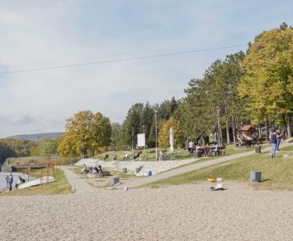 A peaceful park scene with riverside path, trees, and playground, perfect for a family outing.